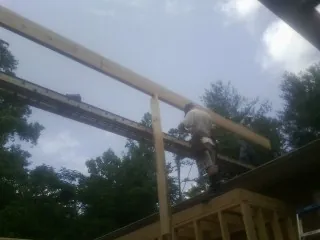 Carpenter setting a ridge beam over a new addition frame — Ice Dam Removal by Roofing Brothers in Tatum