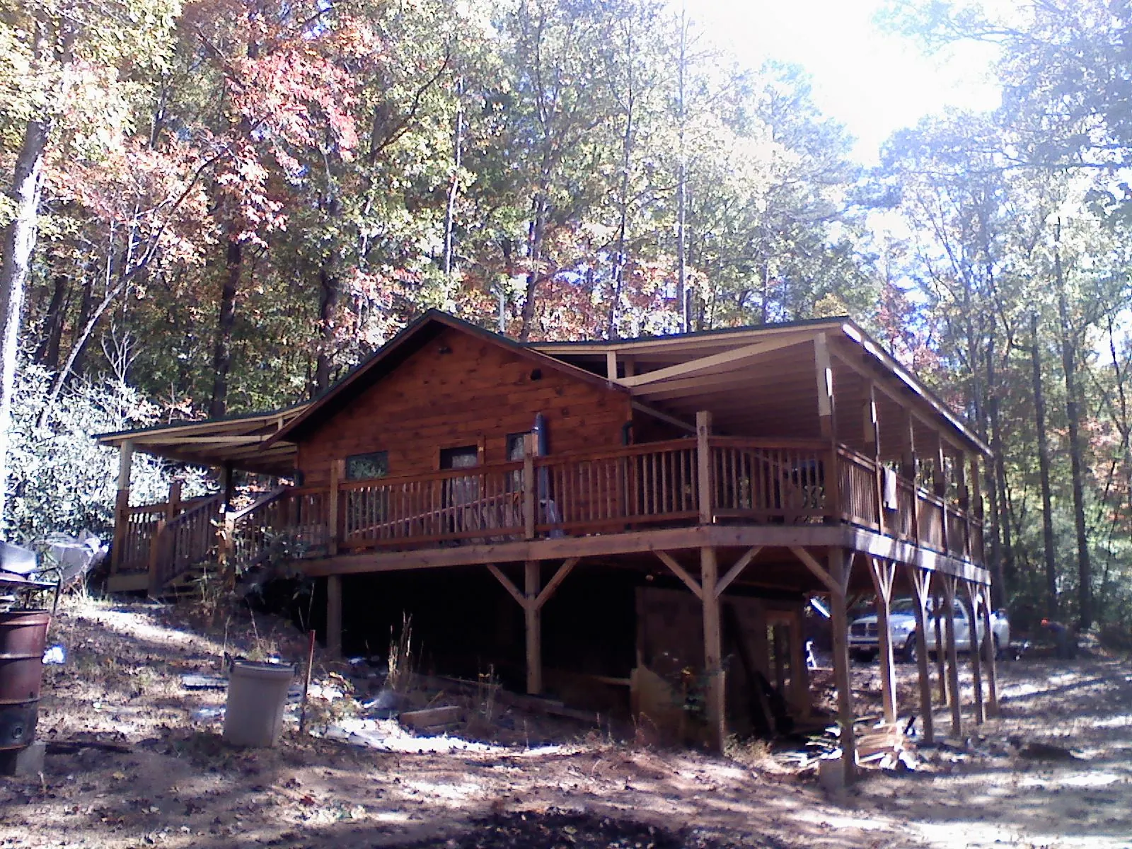 Log cabin with a wraparound porch and metal roof in the fall in Tatum