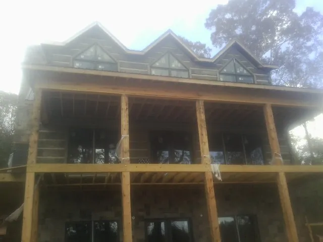 Dormers and porch framing on a large log home under construction — Roof Coating work by our crew in Tatum