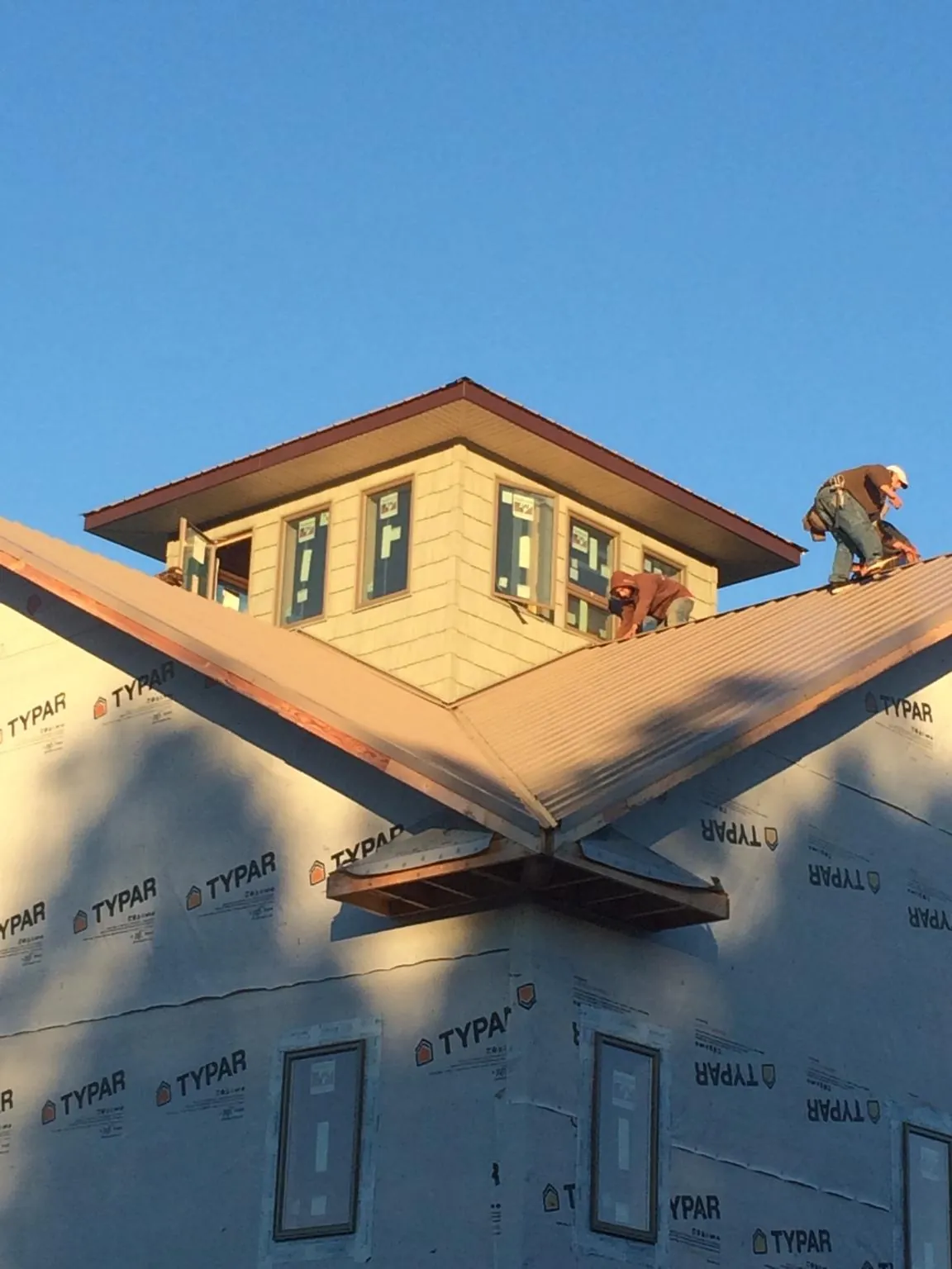 Roofers working around a rooftop cupola on a new metal roof at sunset — Roof Waterproofing in Tatum by Roofing Brothers